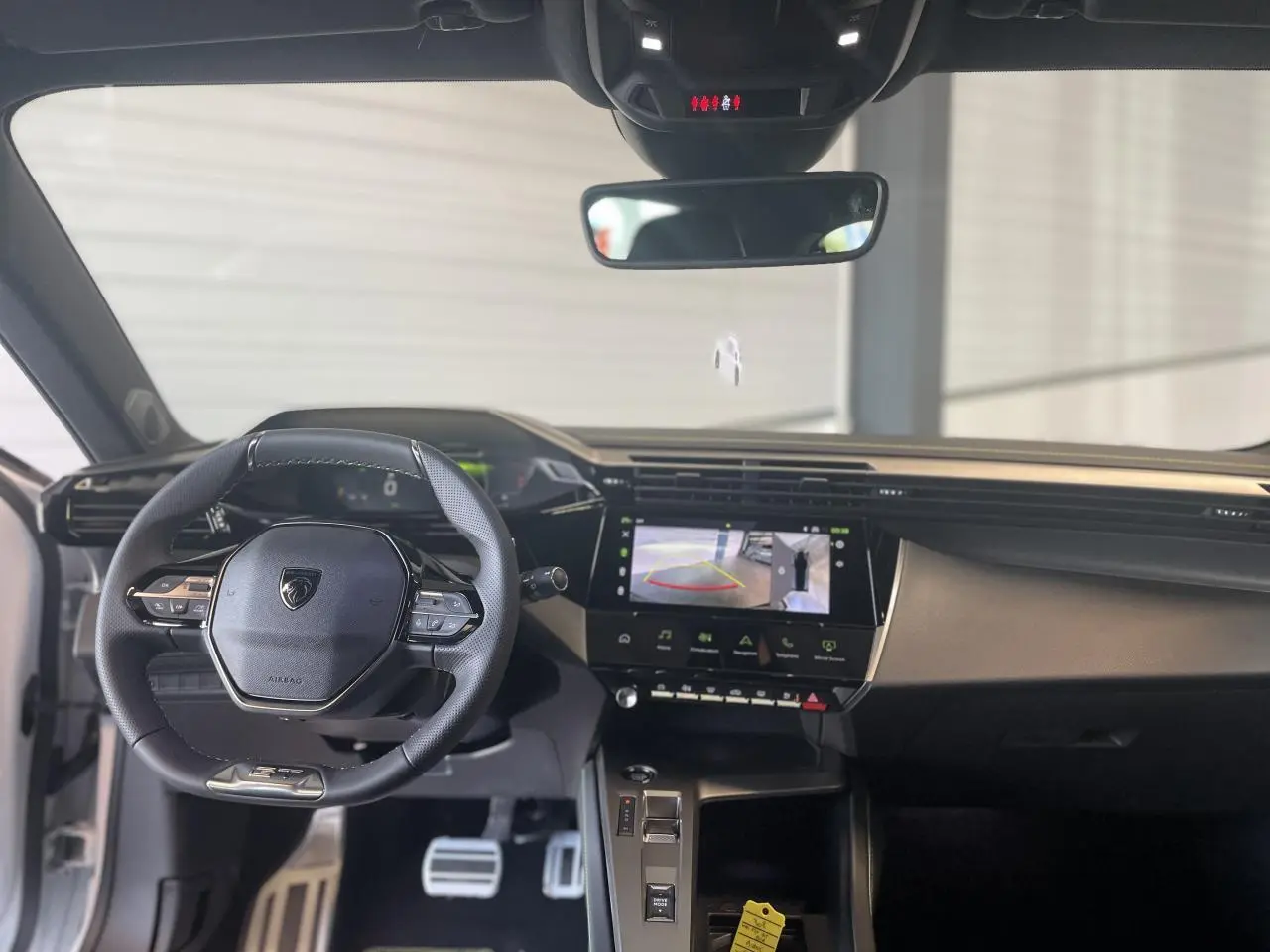 Vue intérieure avant de la Peugeot 308 2025 avec volant cuir, écran tactile et tableau de bord numérique.