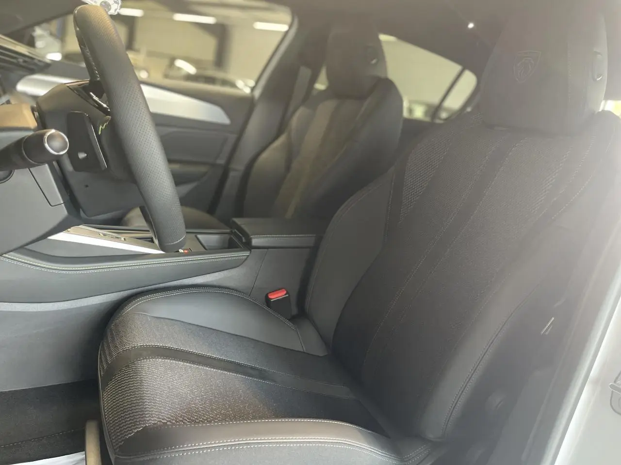 Sièges avant en tissu et cuir noir avec logo Peugeot embossé, vue intérieure côté conducteur de la 308 GT 2025.