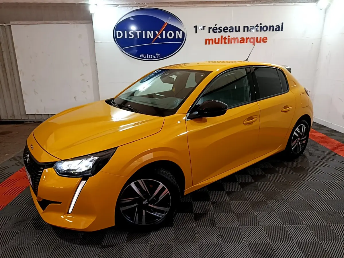 PEUGEOT 208 jaune vue 3/4 avant droit, feux LED allumés, jantes alliage noires, dans un showroom intérieur.