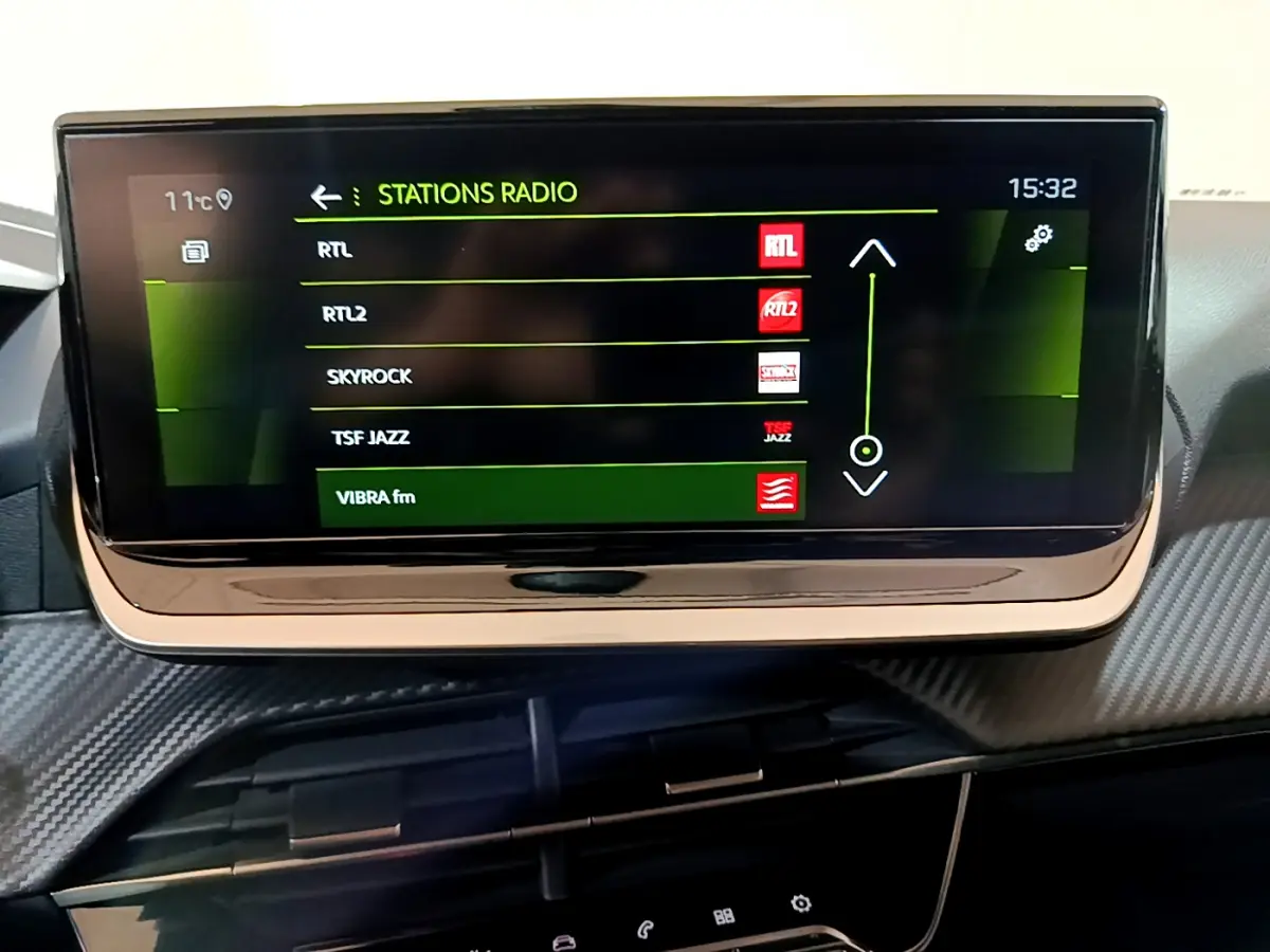 Écran tactile central affichant les stations radio dans l'habitacle d'une Peugeot 208 jaune 2023.