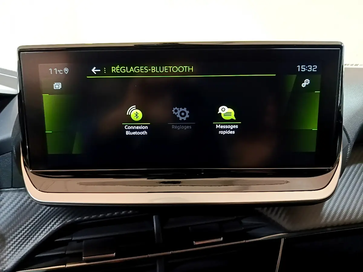 Écran tactile central de la Peugeot 208 jaune 2023 affichant les réglages Bluetooth en intérieur.