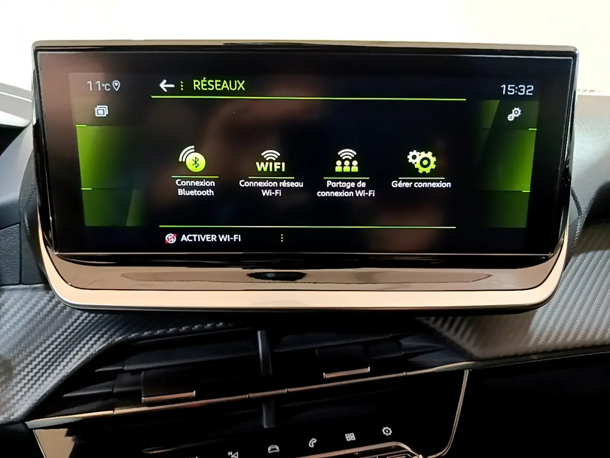 Écran tactile central affichant les options de connexion Bluetooth et Wi-Fi dans l'habitacle d'une Peugeot 208 jaune.
