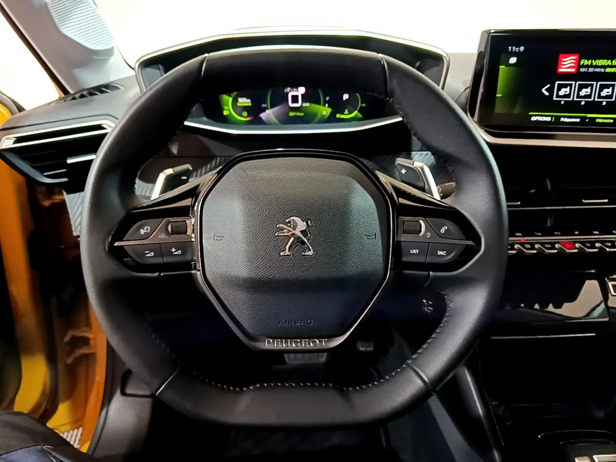 Volant cuir Peugeot 208 jaune 2023 vu de face avec tableau de bord numérique et écran tactile central.