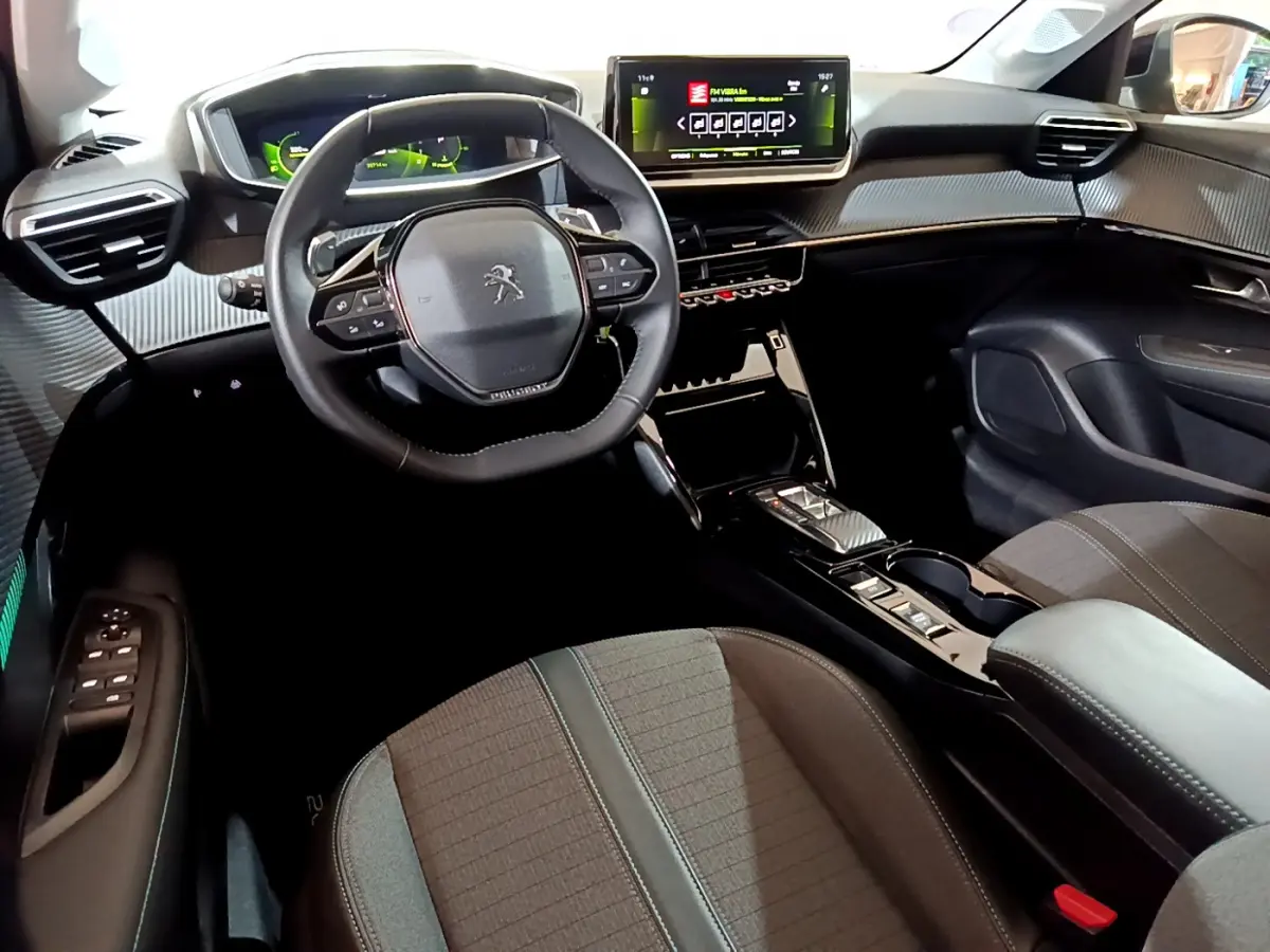 Intérieur de la Peugeot 208 PureTech 100 vue côté conducteur, volant cuir et écran tactile central lumineux.