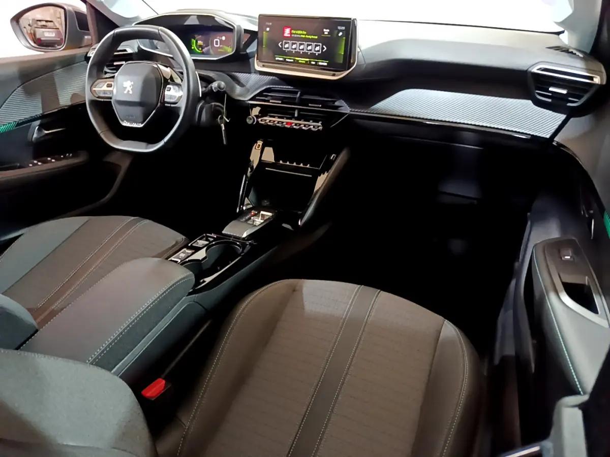 Vue intérieure côté passager avant du tableau de bord et volant cuir de la Peugeot 208 PureTech 100 S&S EAT8 Allure Pack 2023.