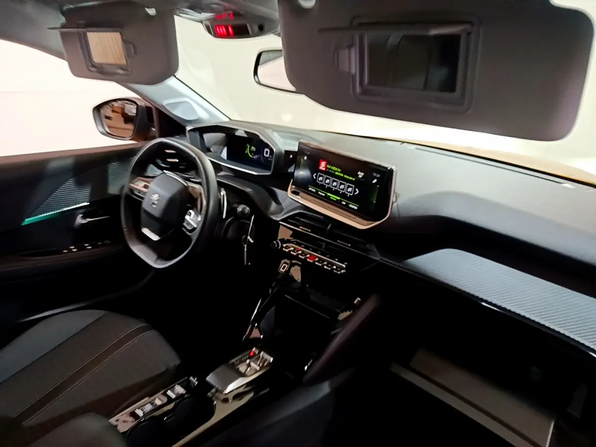 Vue intérieure côté conducteur de la Peugeot 208 jaune 2023, tableau de bord avec écran tactile et volant cuir multifonctions.