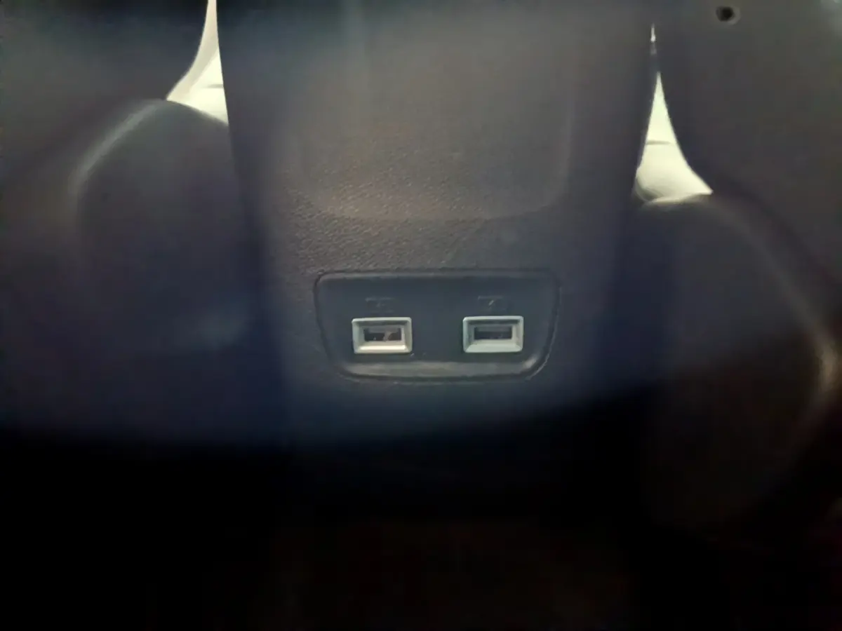 Prise double USB arrière intégrée au dossier central noir de la Peugeot 208 jaune 2023 vue de près