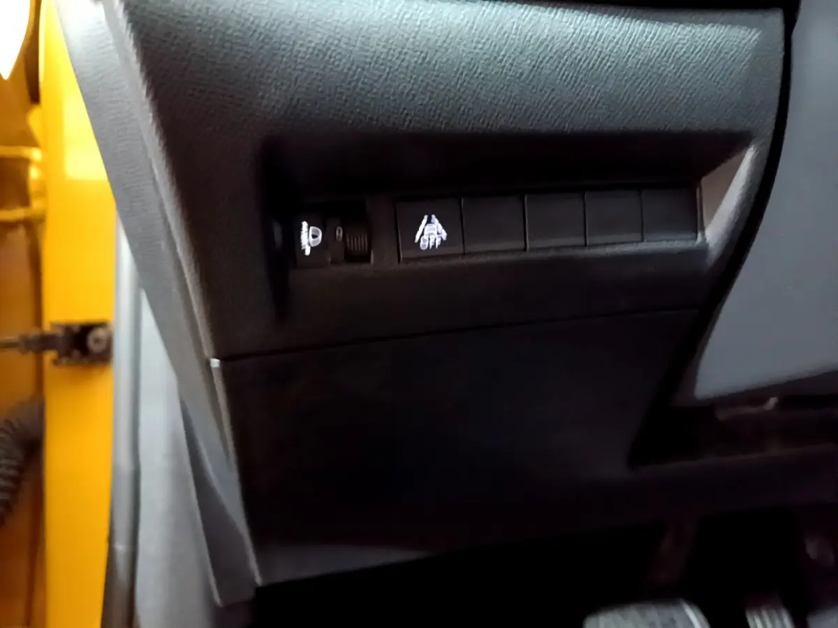 Détail des commandes d'aide à la conduite sur le côté gauche d'une Peugeot 208 jaune 2023.