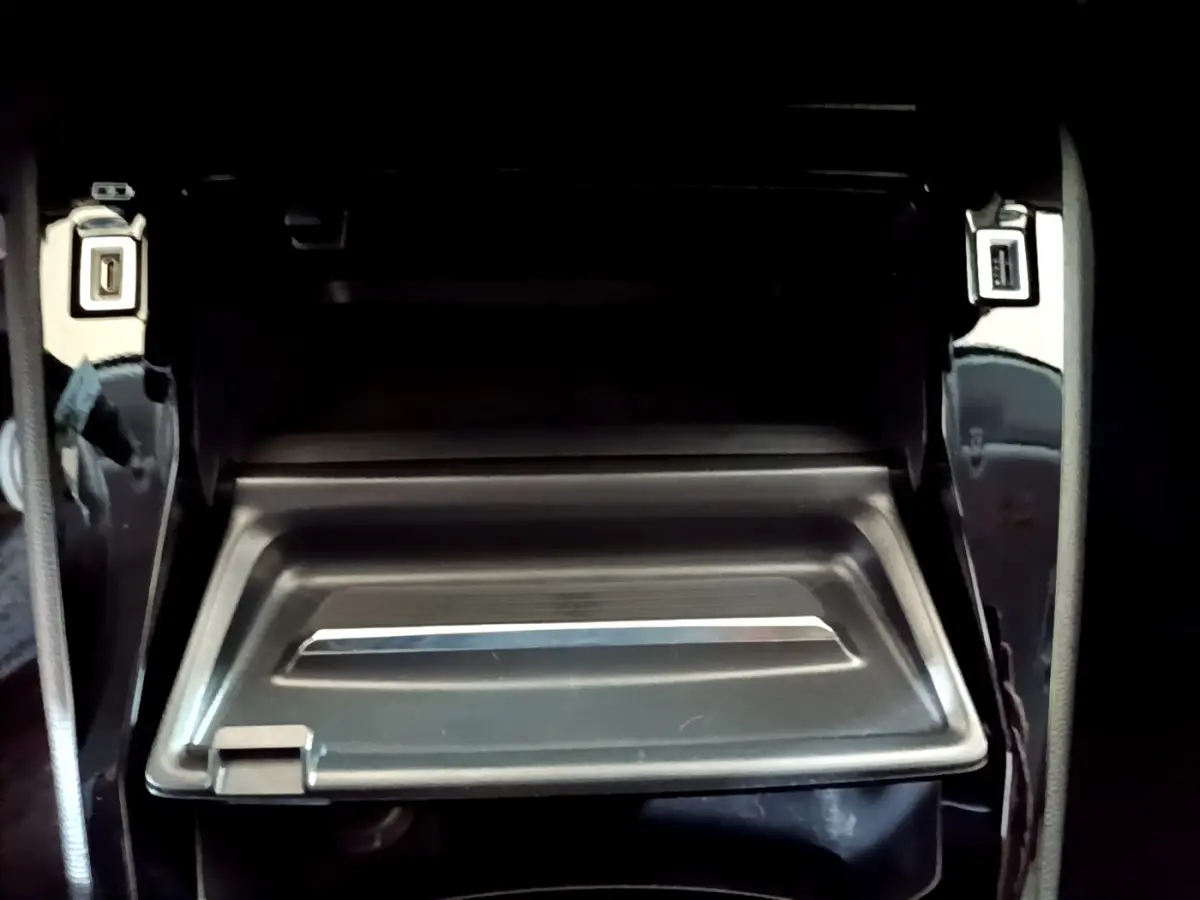 Gros plan sur la boîte à gants ouverte de la Peugeot 208 jaune, montrant son intérieur noir et sa finition sobre.