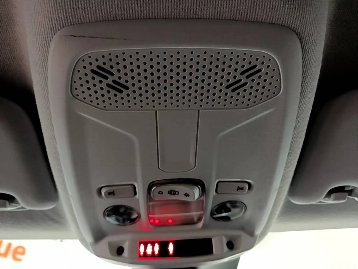 Détail du plafonnier gris clair avec commandes d'éclairage et affichage digital rouge dans une Peugeot 208 jaune.