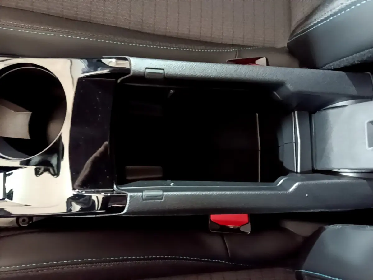 Vue plongeante sur la console centrale noire et les sièges en tissu gris du Peugeot 208 jaune 2023 Allure Pack