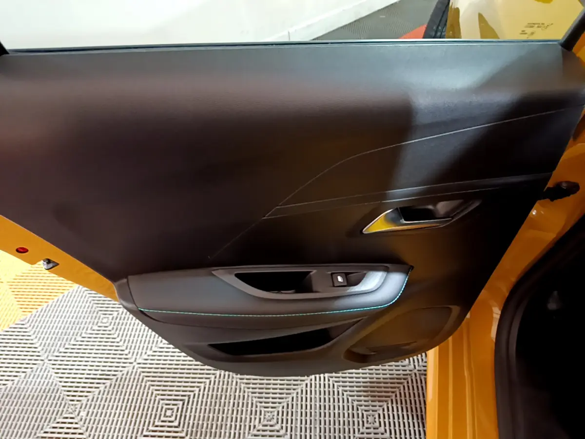 Vue intérieure sur la porte avant gauche noire avec surpiqûres bleues d'une Peugeot 208 jaune 2023 Allure Pack