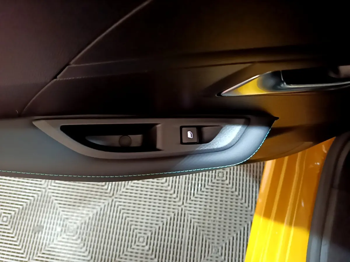 Poignée intérieure côté gauche avec bouton de verrouillage sur porte jaune vif d'une Peugeot 208 2023.