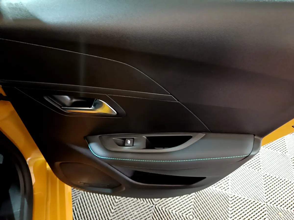 Vue rapprochée de la porte côté gauche jaune de la Peugeot 208 2023 avec poignée argentée et couture bleue.