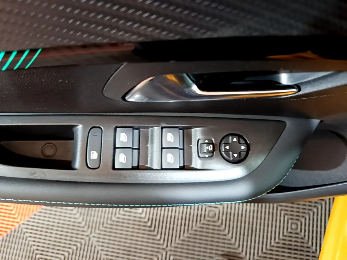Gros plan sur la commande des vitres et rétroviseurs côté conducteur de la Peugeot 208 jaune 2023.