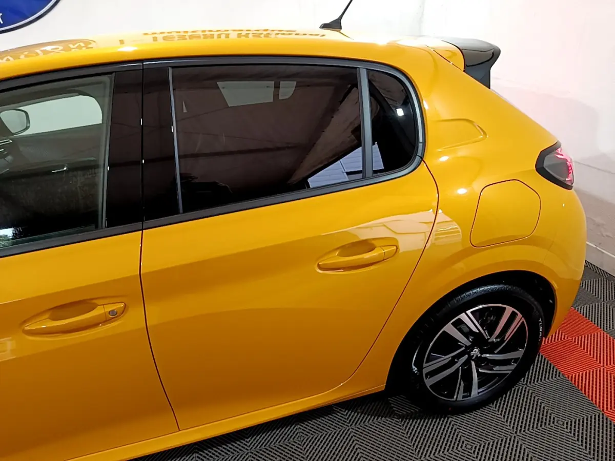Profil arrière droit d'une Peugeot 208 jaune 2023 avec jantes alliage et vitres teintées.