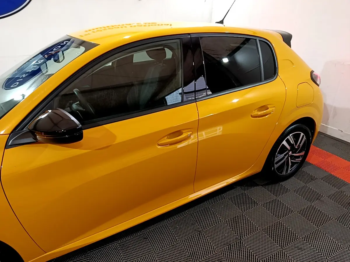 Vue latérale droite d'une Peugeot 208 jaune vif avec rétroviseur noir brillant et jantes alliage design.