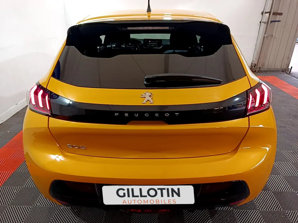 Vue arrière d'une Peugeot 208 jaune 2023 avec feux LED et logo lion sur hayon noir brillant.