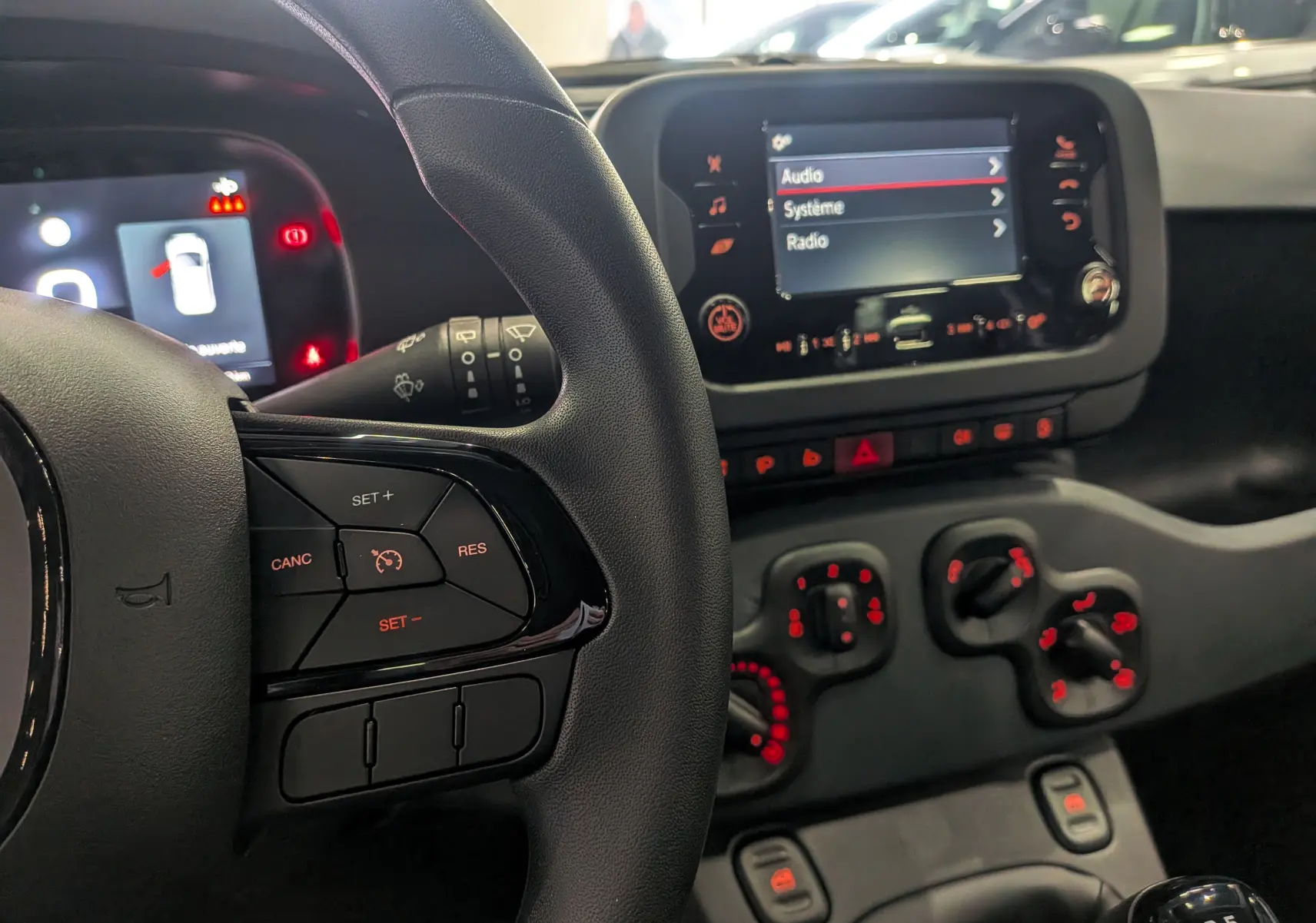 Vue rapprochée du tableau de bord et volant noir de la Fiat Panda 1.0 70 CH Hybrid City avec commandes au volant et écran tactile.