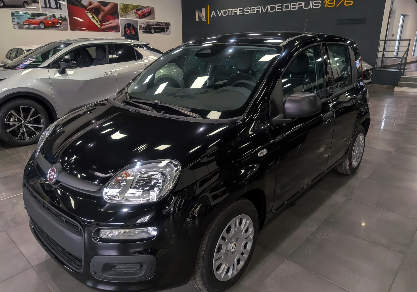 Vue 3/4 avant droite d'une Fiat Panda 1.0 70 CH Hybrid City noire, en showroom avec jantes acier et rétroviseurs noirs.