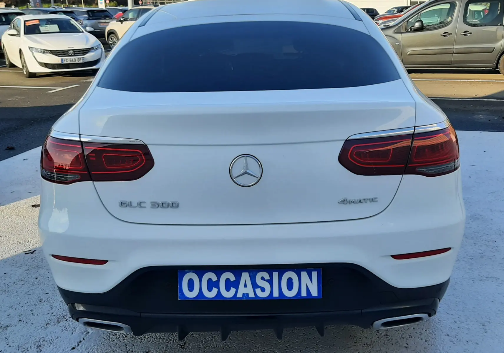 Vue 3/4 arrière droite d’un Mercedes GLC Coupé blanc 2019 avec jantes AMG noires et vitres teintées.