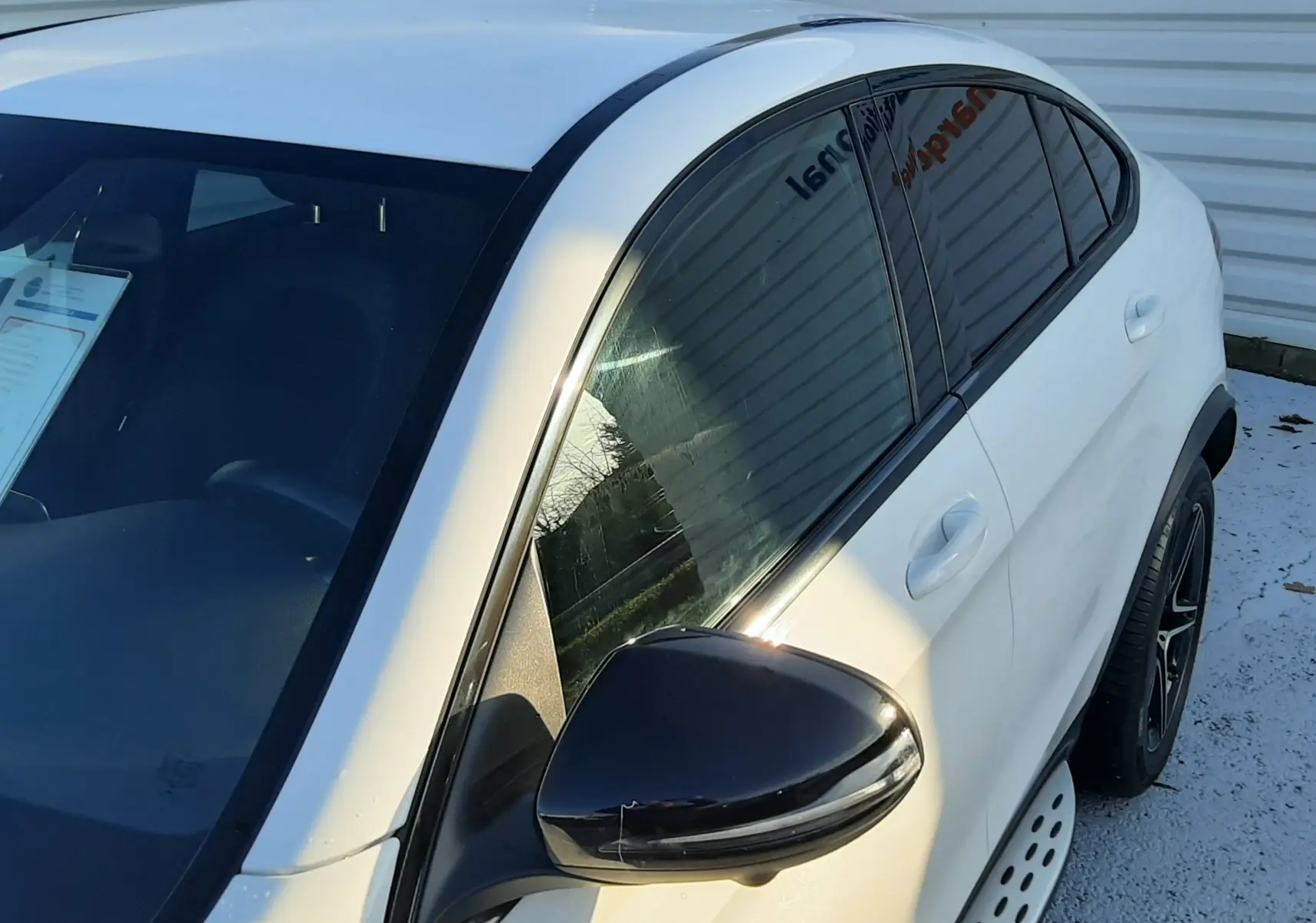 Mercedes GLC Coupé 300 4MATIC AMG blanc vu de profil côté gauche, avec jantes noires à cinq branches.