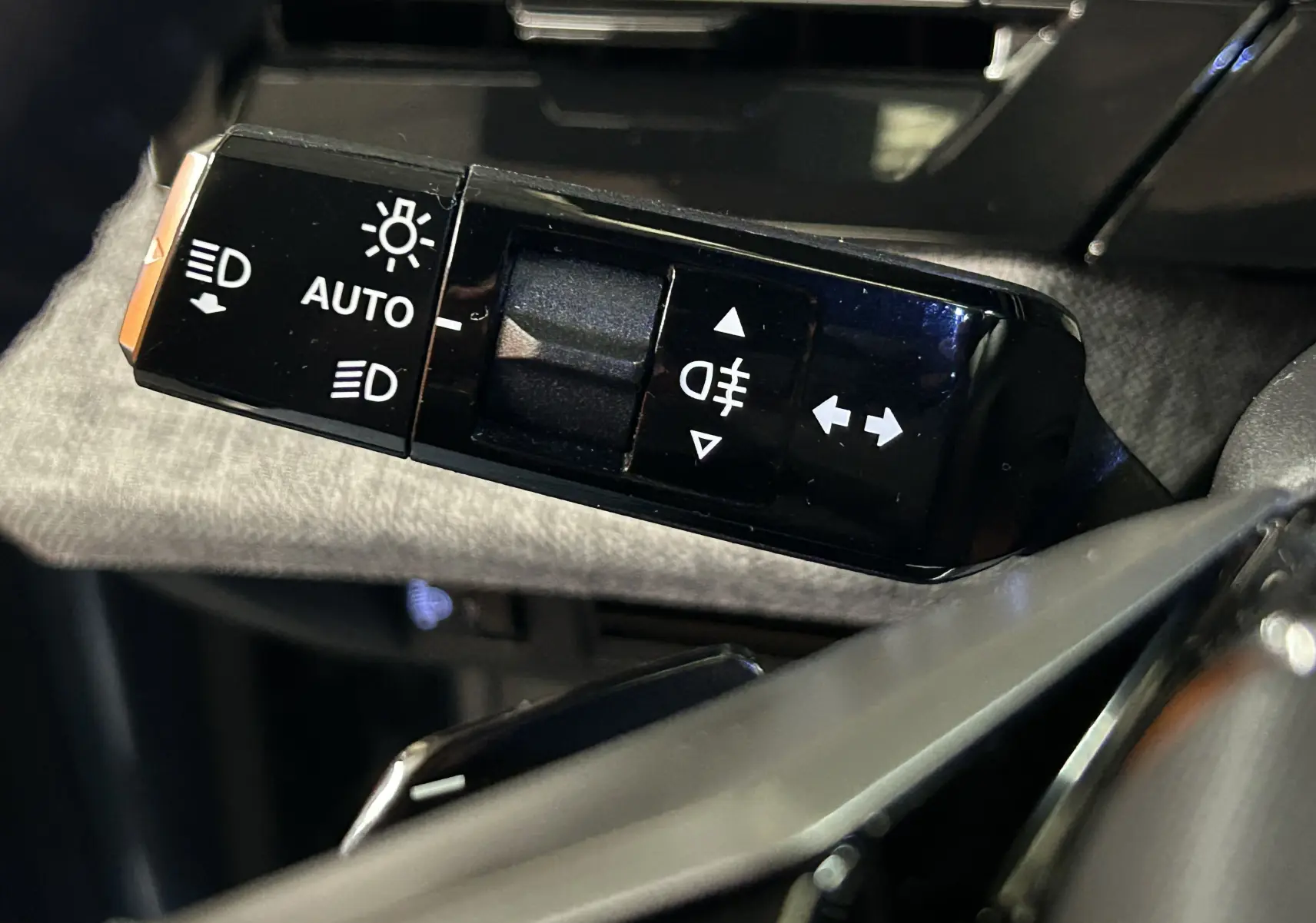 Gros plan sur la commande des feux et clignotants noire à gauche du volant dans l’habitacle d’un Peugeot 3008 noir 2025.