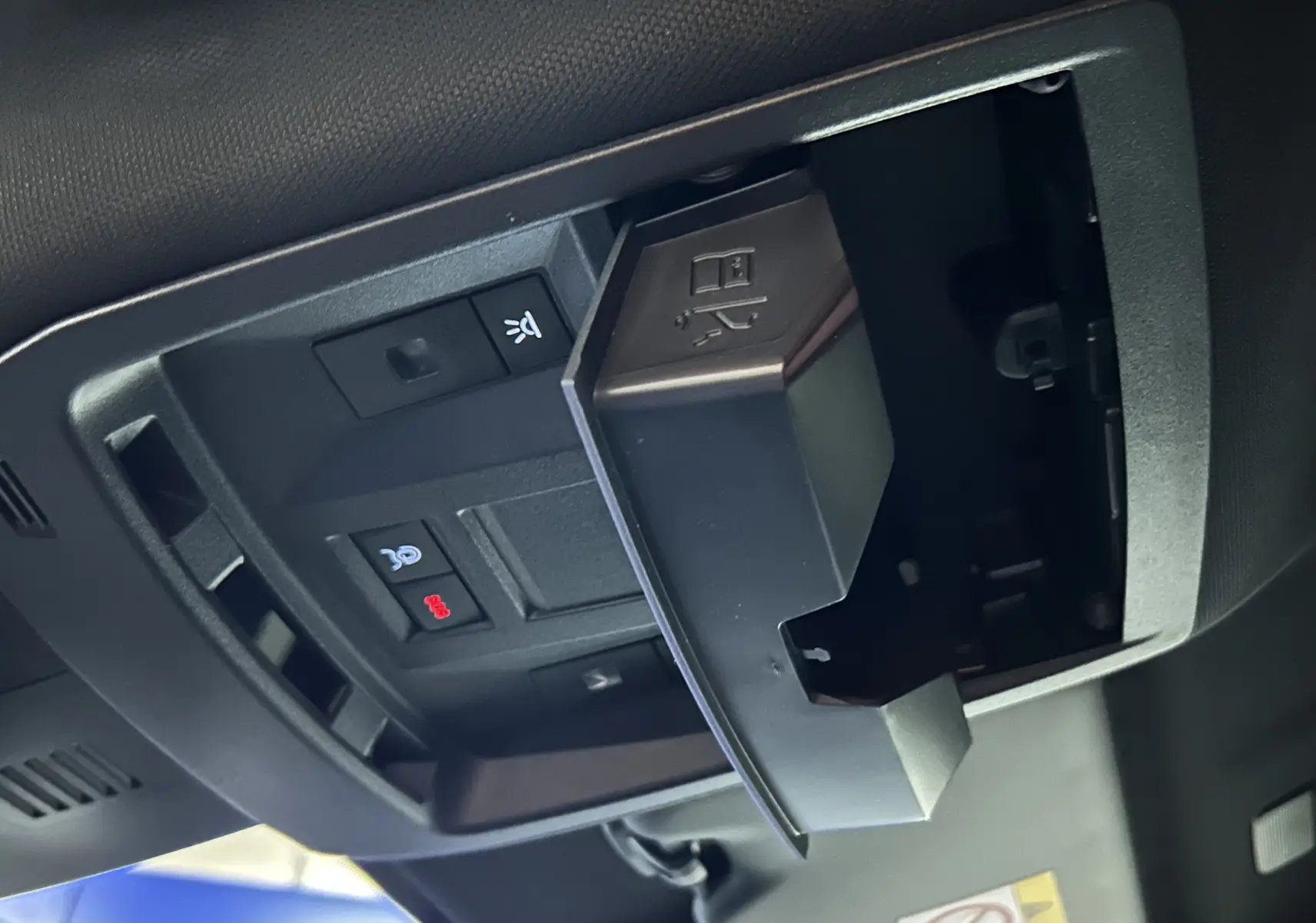 Gros plan sur le compartiment ouvert au plafond avec boutons de contrôle, intérieur noir du Peugeot 3008 III Hybrid 2025.