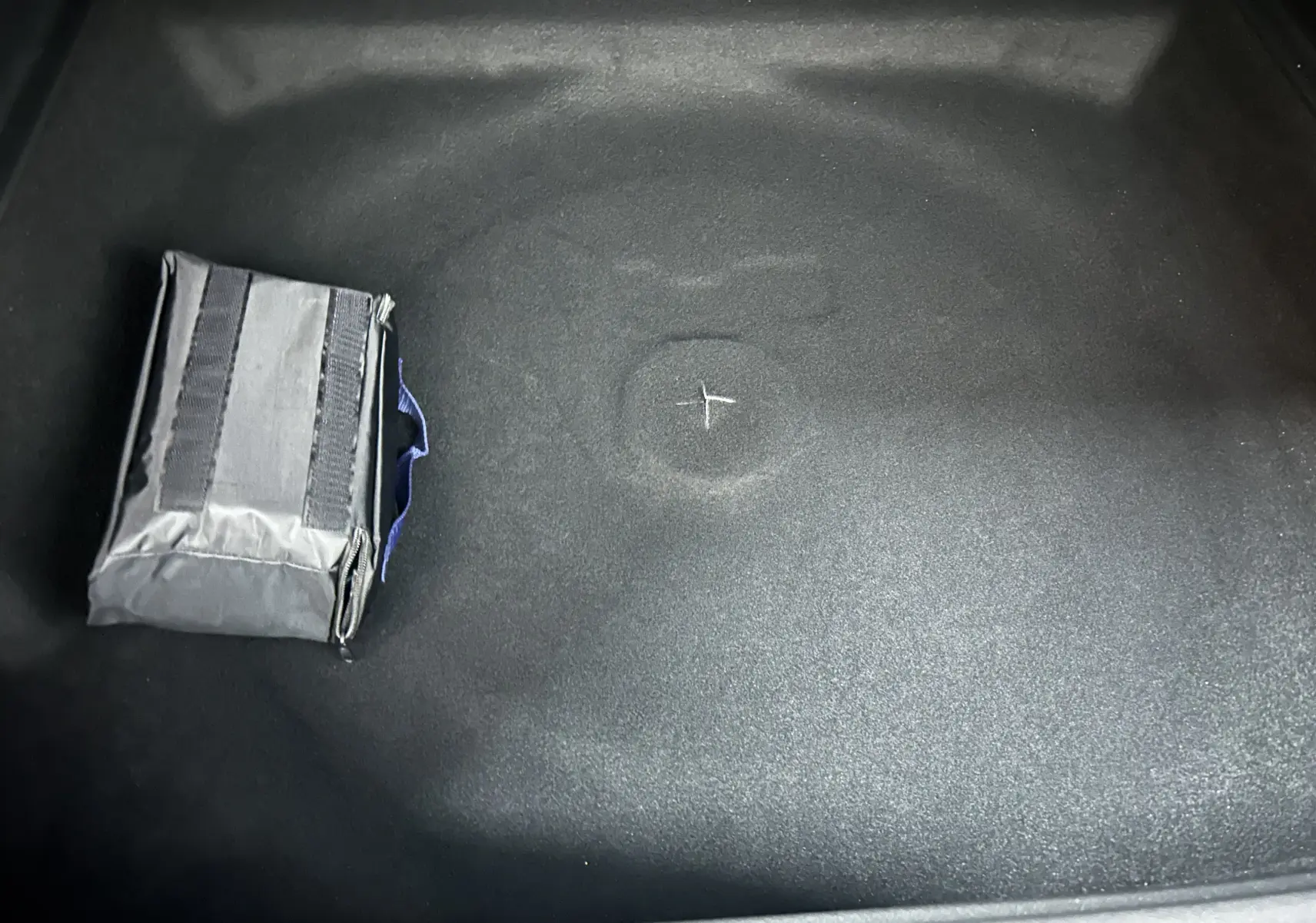 Détail du coffre noir du Peugeot 3008 III Hybrid 145 e-DSC6 Allure avec une trousse de secours grise posée.