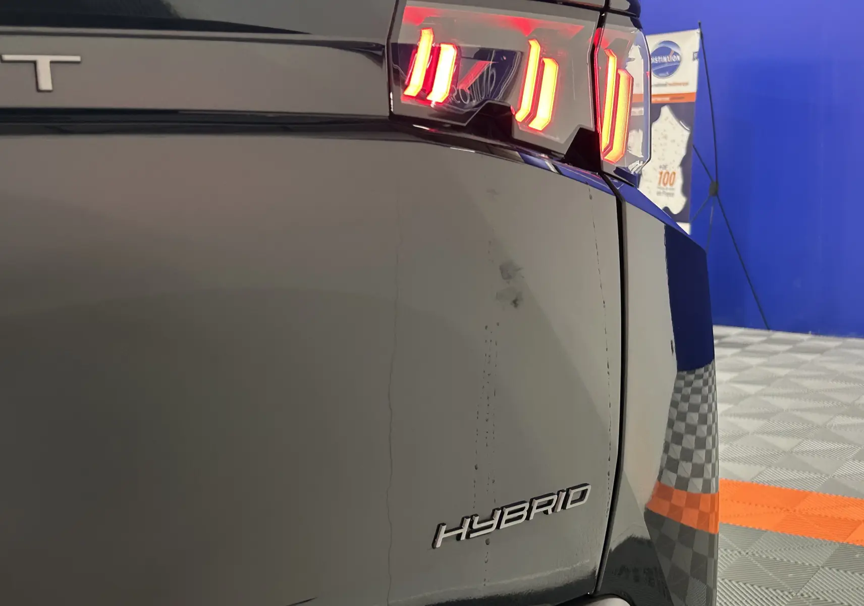 Gros plan sur l'arrière droit noir du Peugeot 3008 Hybrid 2025, mettant en valeur le feu arrière allumé et l'inscription HYBRID.