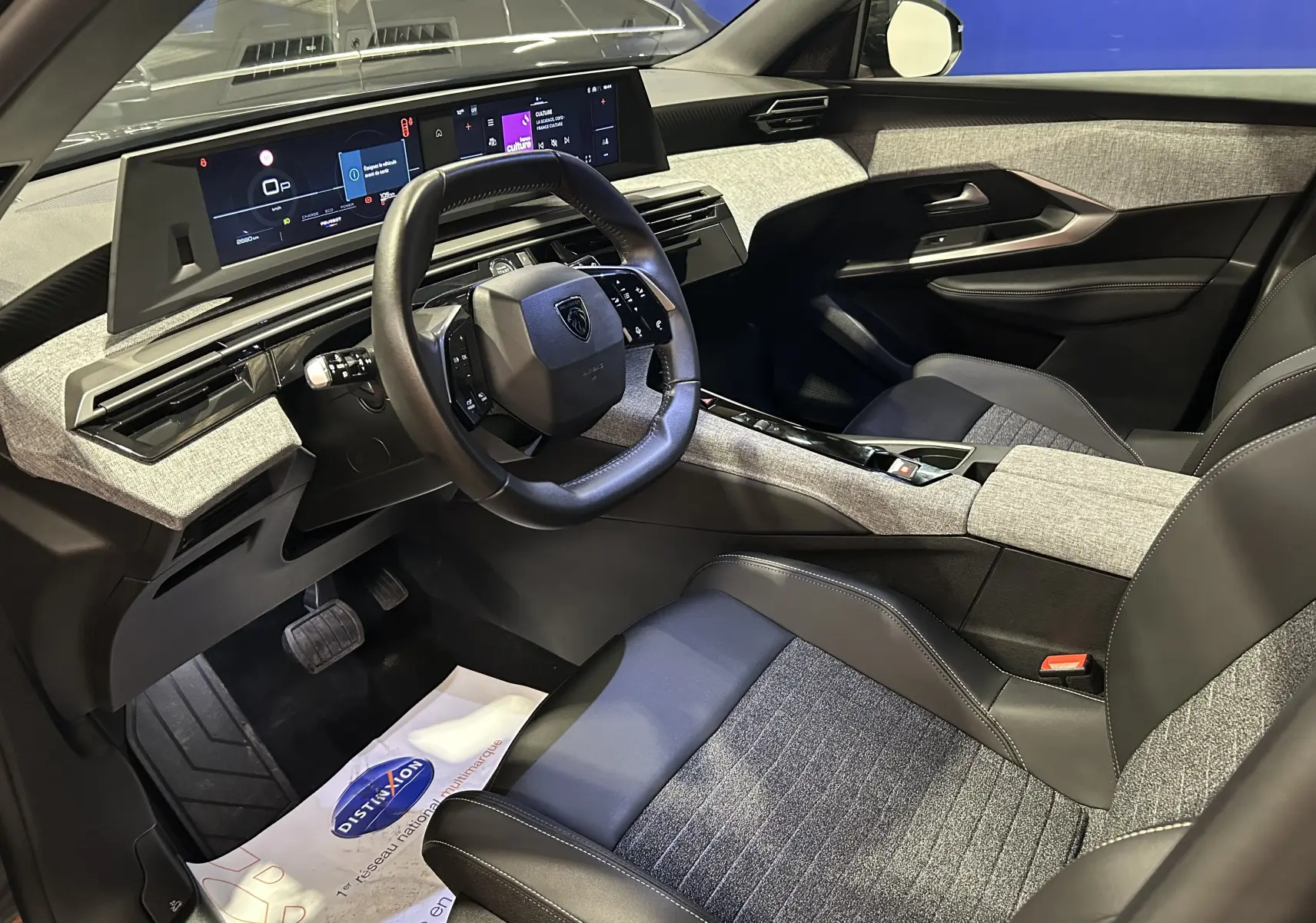 Intérieur avant droit du Peugeot 3008 III Hybrid 145 Allure 2025, avec sellerie bi-matière grise et noire et tableau de bord numérique.