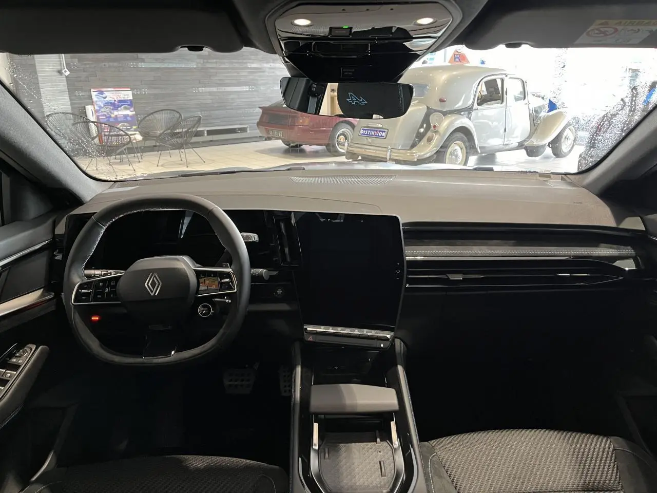 Vue intérieure avant du Renault Austral 2025 gris, avec tableau de bord moderne et grand écran tactile vertical.