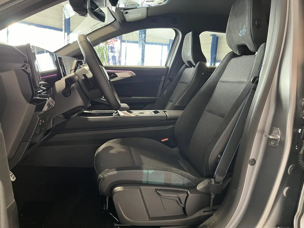 Vue intérieure côté gauche du siège avant gris avec surpiqûres bleues et appuie-tête Alpine du Renault Austral 2025.