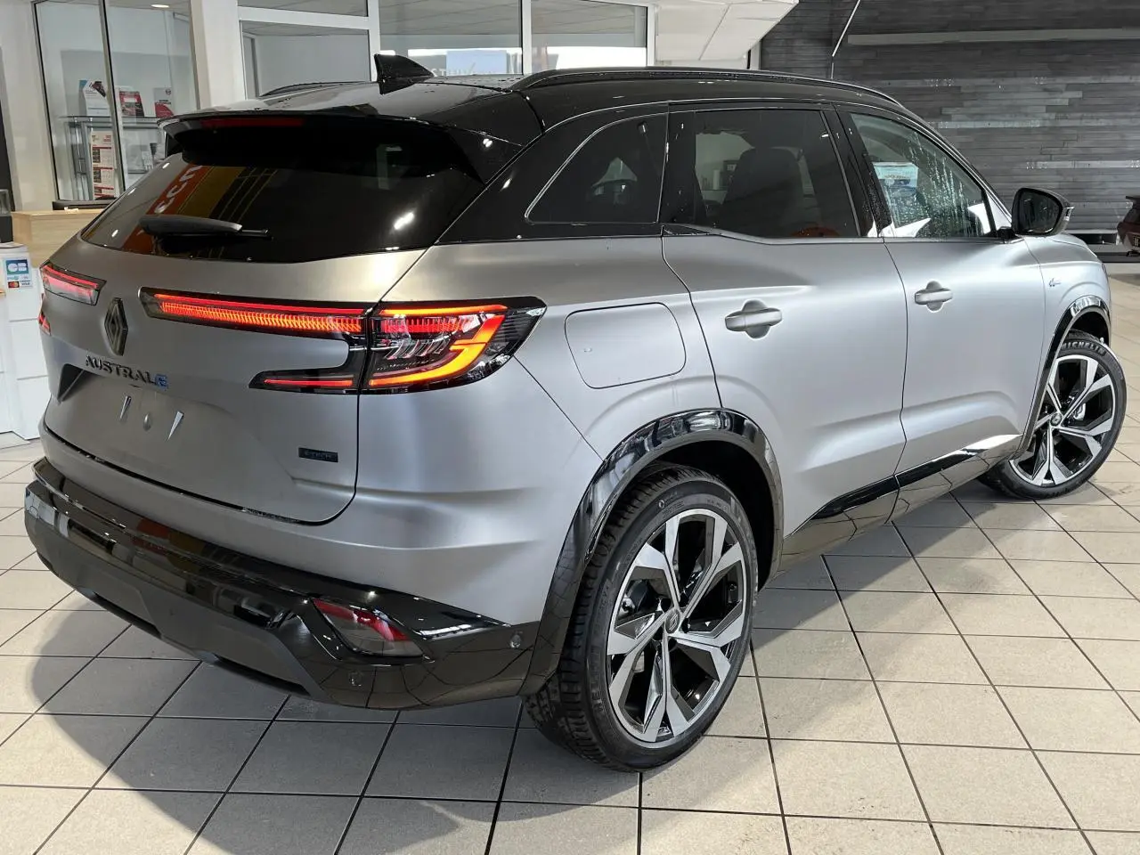 Vue 3/4 arrière droite du Renault Austral gris avec toit noir étoilé et jantes alliage 20 pouces diamantées.