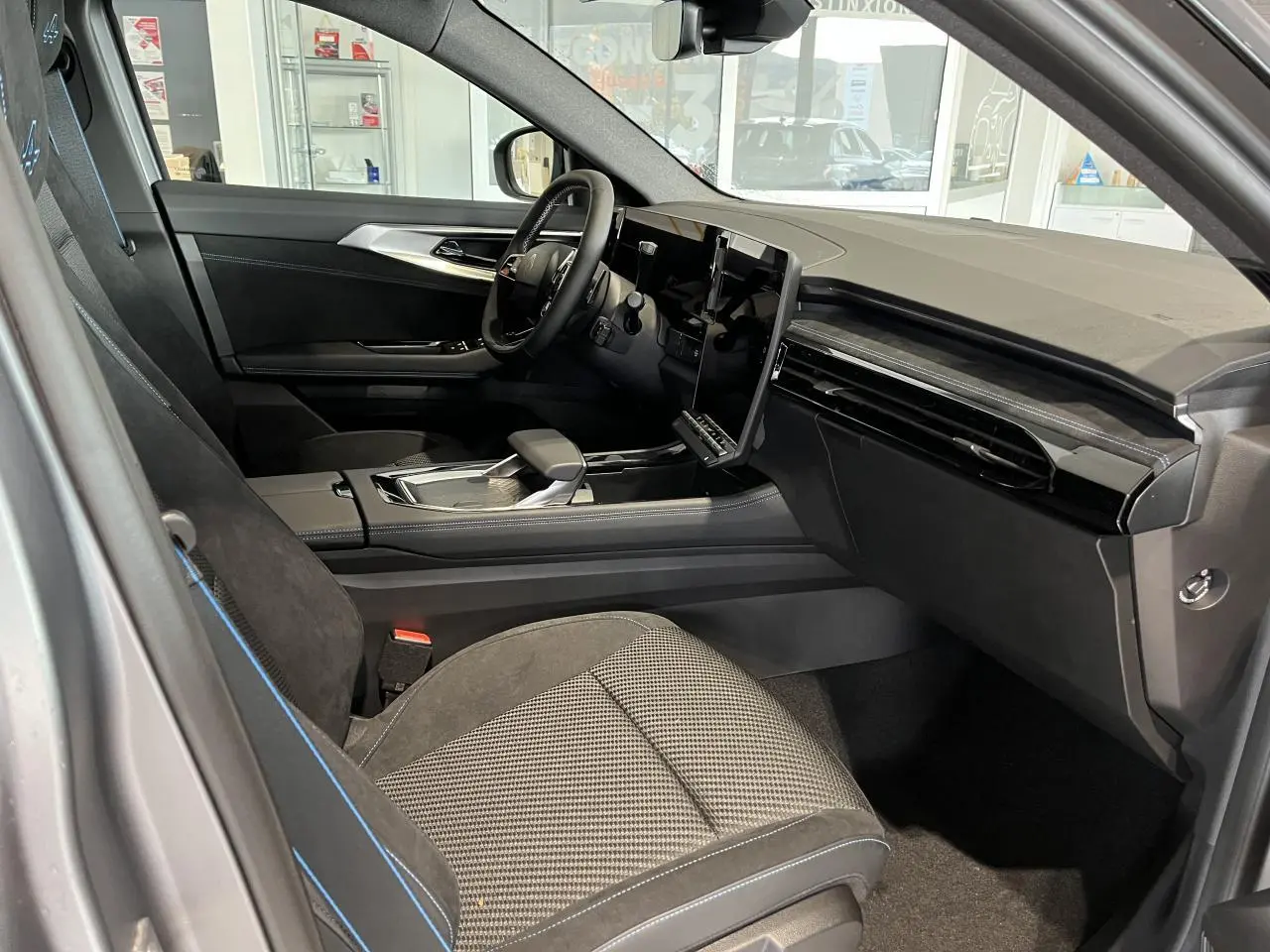 Intérieur côté conducteur du Renault Austral 2025 gris, avec sellerie Alcantara noire et écran tactile central vertical.