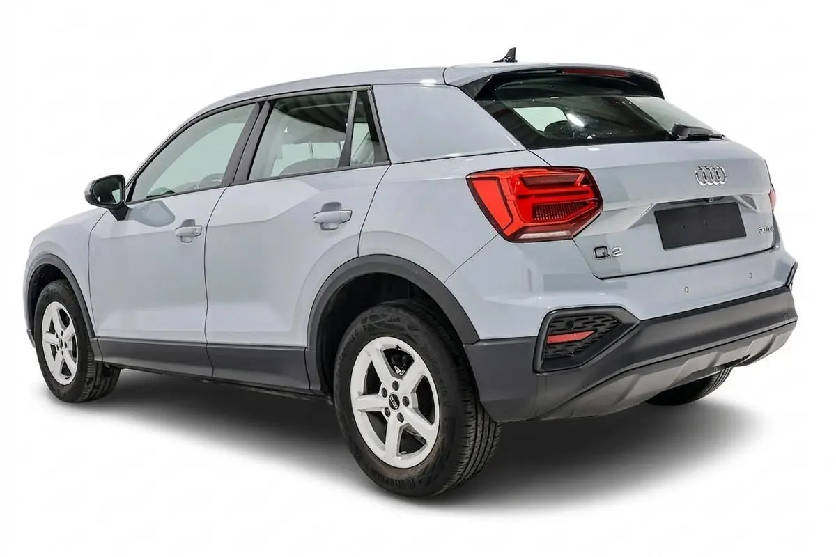 Audi Q2 gris vue 3/4 arrière droit, hayon fermé et feux arrière rouges bien visibles.