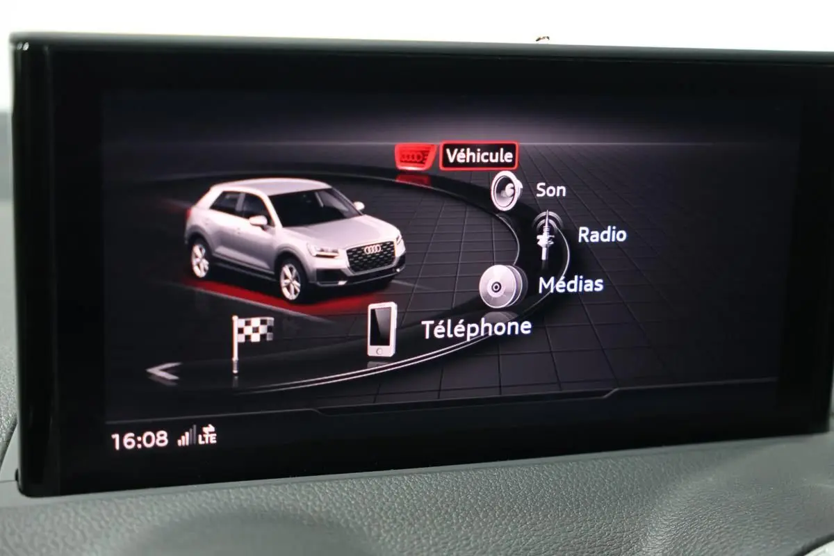 Écran central affichant l'interface multimédia avec une Audi Q2 grise vue de trois quarts avant virtuelle.