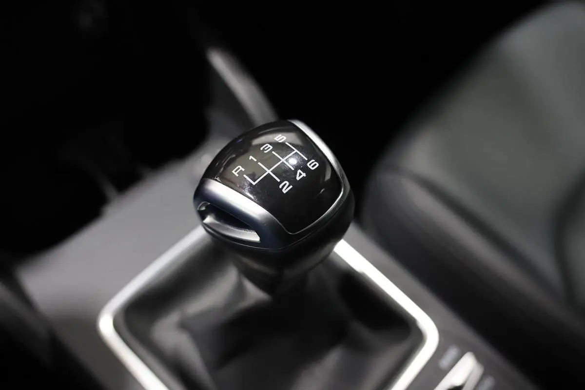 Le levier de vitesses manuel noir de l'Audi Q2 TFSI 110, vue rapprochée de l'intérieur côté conducteur.