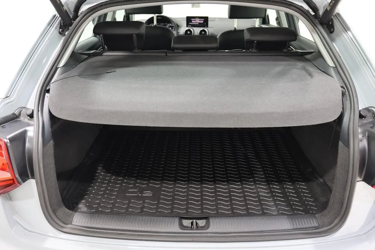 Coffre ouvert vu de l'arrière d'un Audi Q2 gris 2023 avec hayon électrique et intérieur noir.