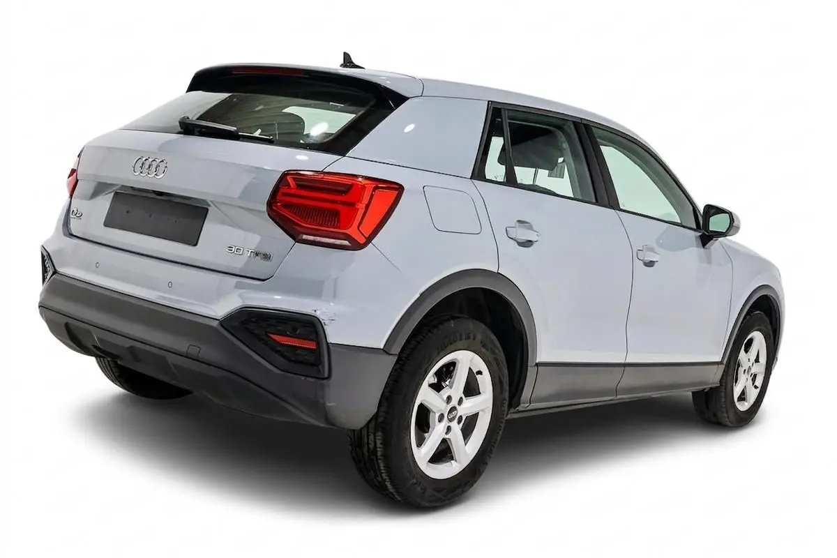 Audi Q2 gris vue 3/4 arrière droit, mettant en valeur ses feux arrière rouges et ses jantes blanches.