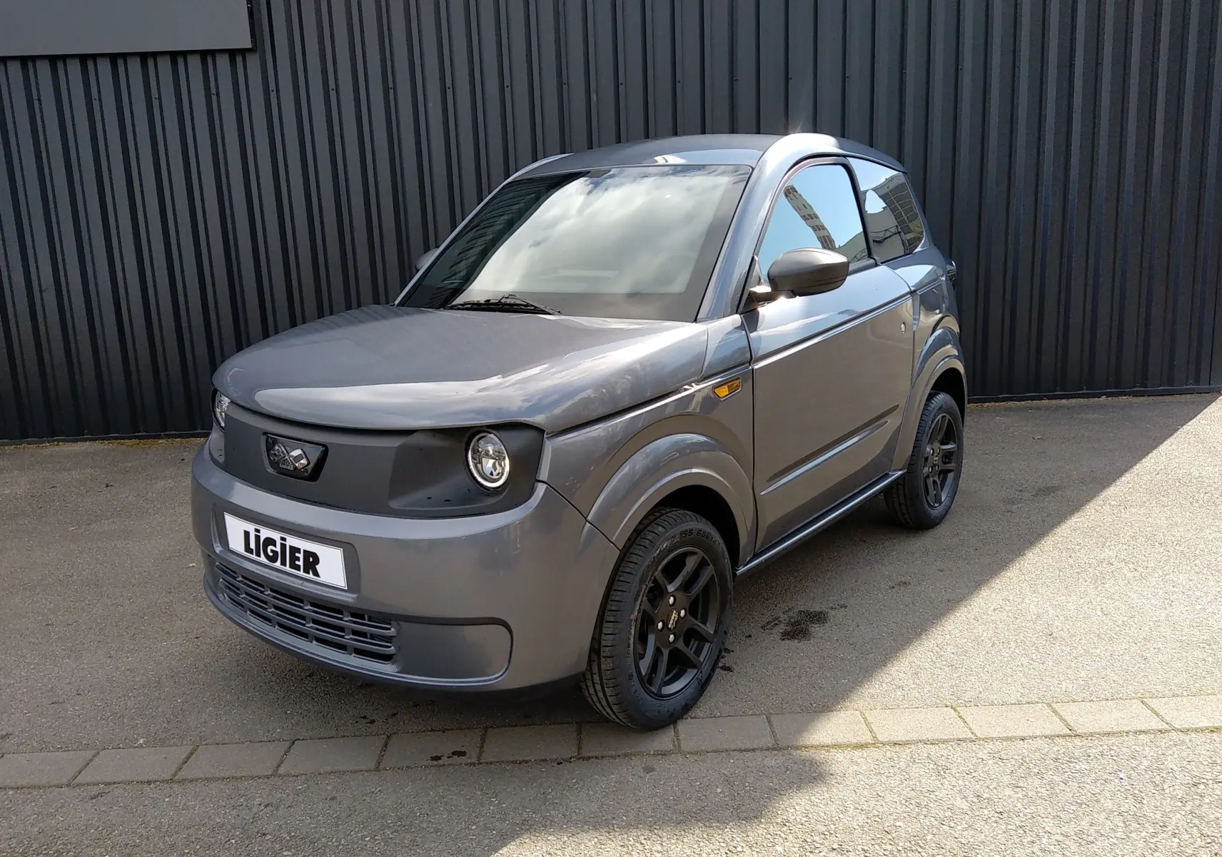 Vue 3/4 avant droit d'une Ligier Myli REVO D+ MAX gris graphite avec jantes noires et calandre sombre.