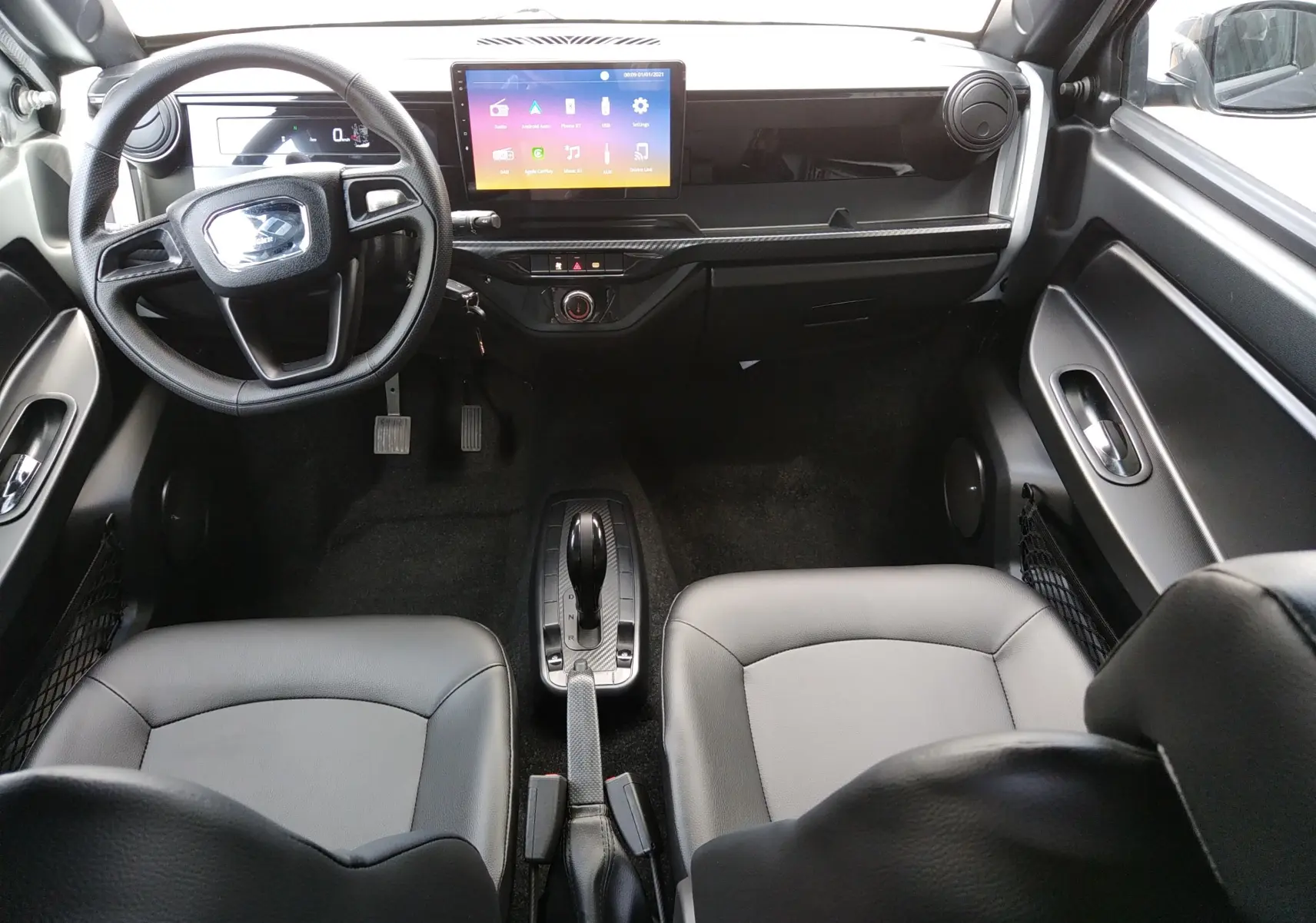 Vue intérieure avant de la Ligier Myli REVO D+ MAX 2026, avec tableau de bord noir, écran tactile central et sièges cuir noir.