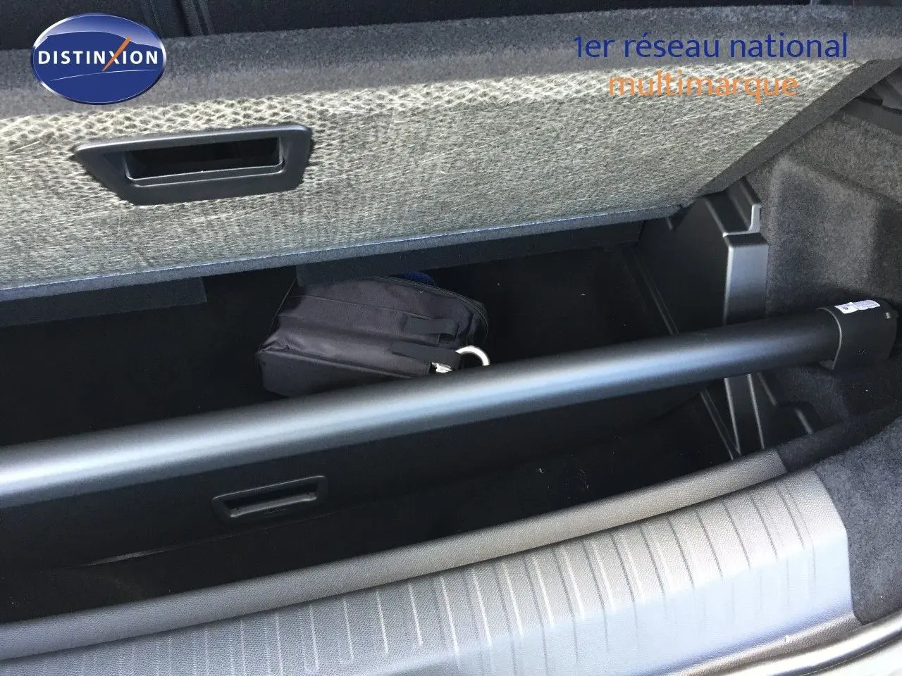 Coffre ouvert du Peugeot 5008 blanc Okenite Metal, montrant le rangement sous plancher avec une trousse noire.