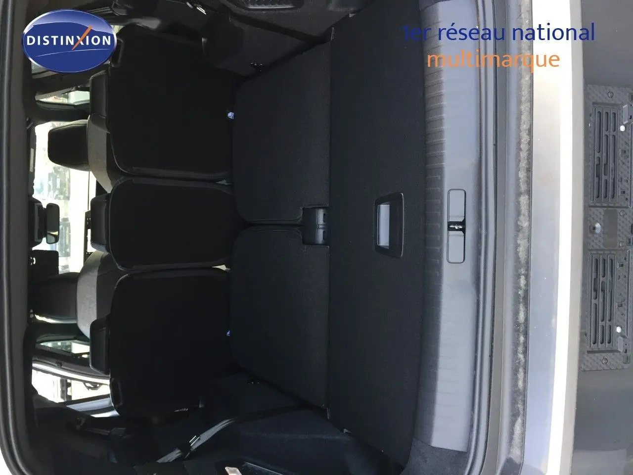 Coffre ouvert du Peugeot 5008 blanc Okenite Metal, montrant la banquette arrière et l'espace de chargement.