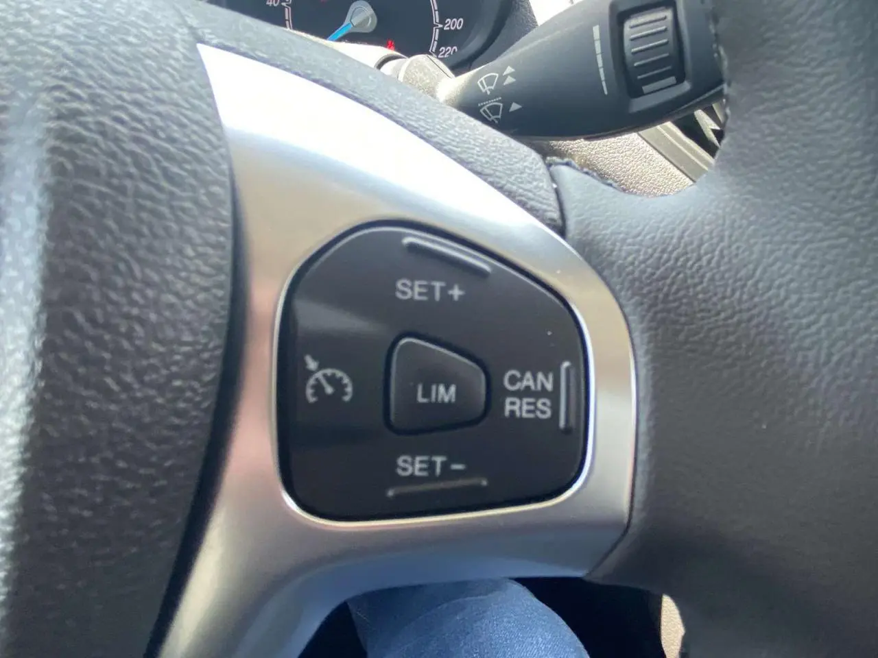 Gros plan sur les commandes du régulateur de vitesse au volant cuir du Ford Tourneo Courier blanc 2022.