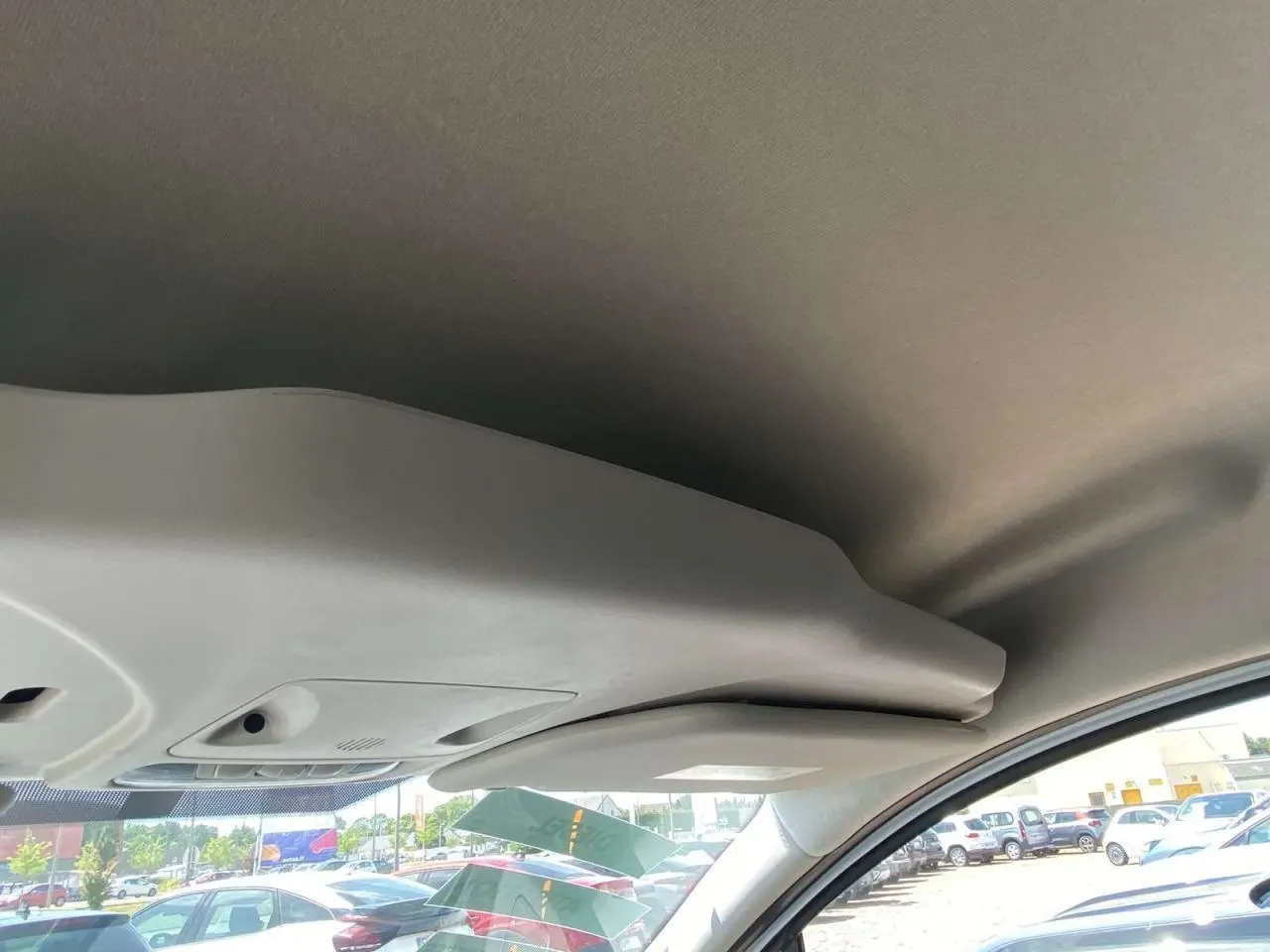 Vue intérieure du plafond et pare-soleil côté conducteur d'un Ford Tourneo Courier blanc 2022, avec parking en arrière-plan.