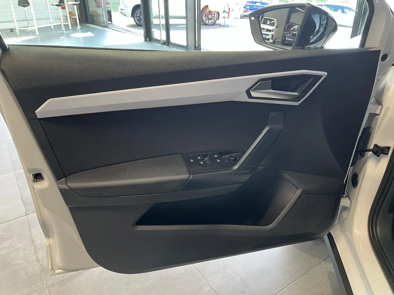 Vue intérieure de la porte avant gauche blanche du SEAT Arona 2024 avec commandes de vitres et rétroviseur.