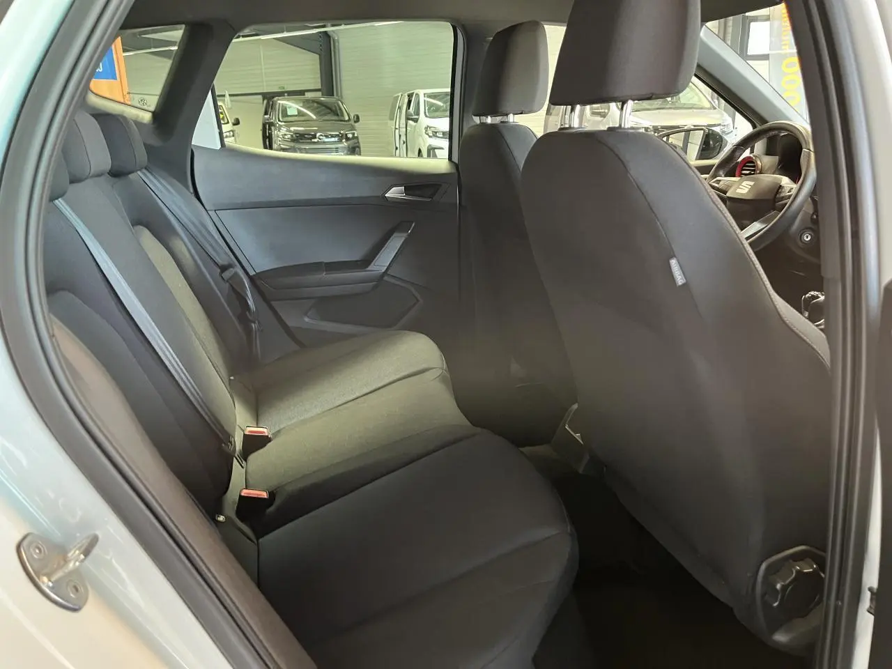 Vue intérieure côté gauche de la banquette arrière noire du SEAT Arona blanc Nevada 2024 avec sièges textile ACERO.