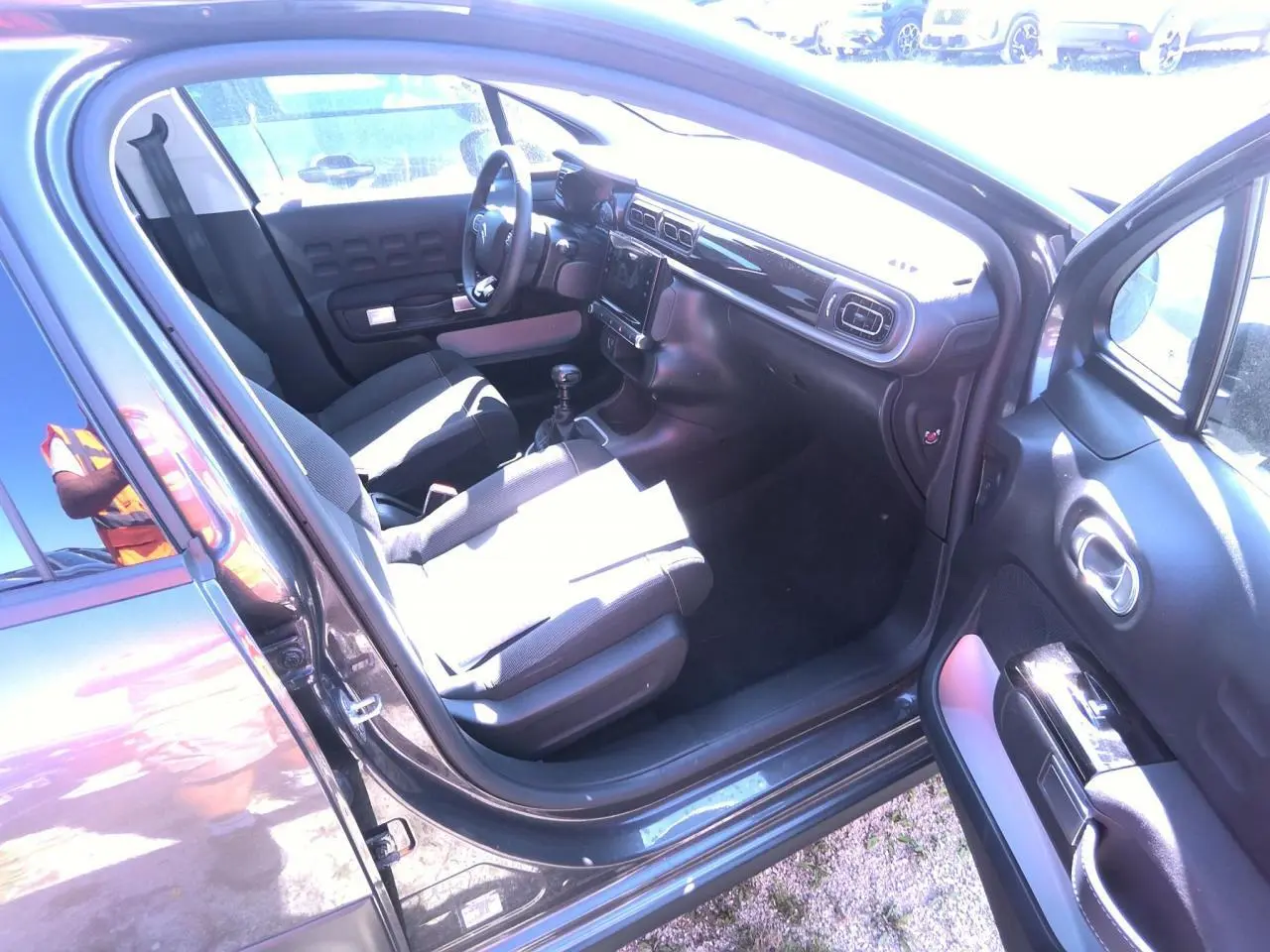 Intérieur avant droit d'une Citroën C3 gris foncé 2024, montrant sièges tissu et tableau de bord noir brillant.