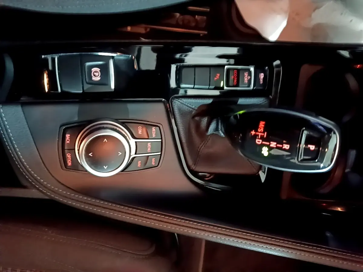 Vue rapprochée de la console centrale noire du BMW X2 2023 avec levier de vitesse automatique et molette de contrôle.